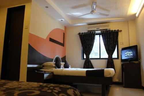 a bedroom with two beds and a tv and a window at Hotel Fortune in Mumbai
