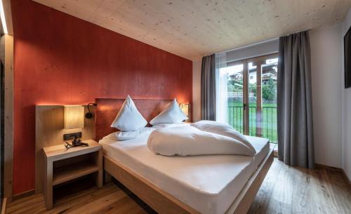 a bedroom with a large bed with a red wall at Hotel Alpenroyal in Castelrotto