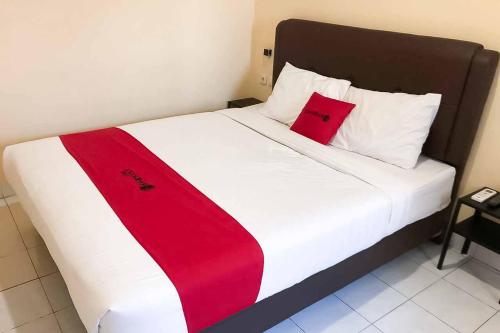 a bed with a red and white blanket on it at RedDoorz @ Pavilion Residence Cikarang in Jakarta