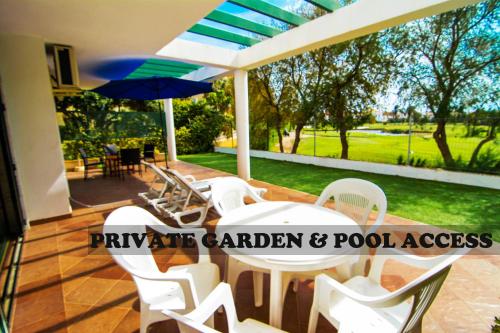 een patio met een tafel en stoelen en een parasol bij Roquetas Beach and Playa Serena Golf Village in Roquetas de Mar