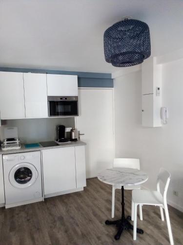 une cuisine avec une table et une machine à laver dans l'établissement le Voili Voilou studio climatisé, à Sète