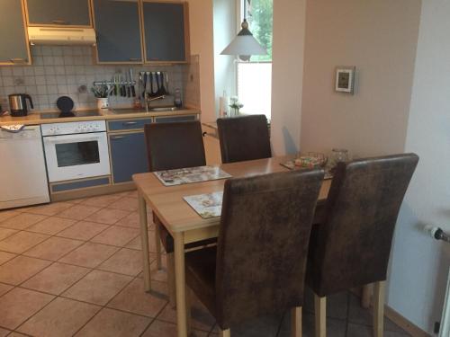 Una cocina con una mesa de comedor y sillas de madera. en Ferienhaushälfte Domeyer Midlum, en Midlum