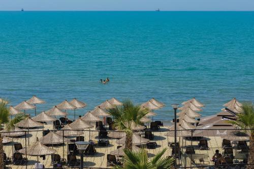 a beach with umbrellas and people in the water at Gloria Palace Hotel & SPA in Golem