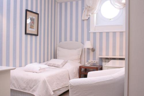 2 Betten in einem Zimmer mit gestreiften Wänden und einem Fenster in der Unterkunft Dom Pugetów in Krakau