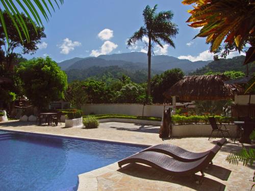 een bankje naast een zwembad met bergen op de achtergrond bij Villa Cata Hotel in El Zaino