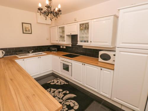 a kitchen with white cabinets and a wooden counter top at The Old Mill in Milford Haven