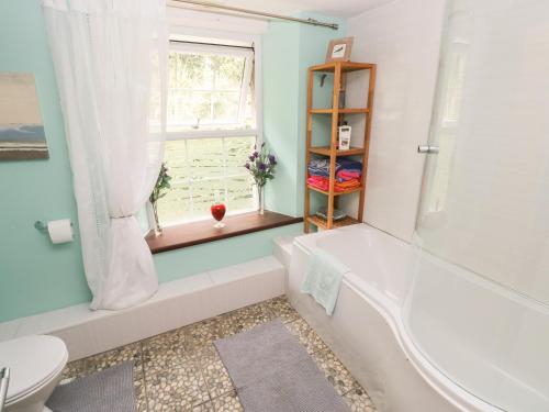 a bathroom with a tub and a toilet and a window at The Old Mill in Milford Haven