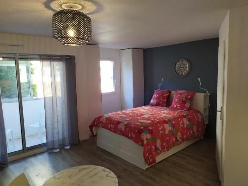 une chambre avec un lit avec une couette rouge dans l'établissement le Voili Voilou studio climatisé, à Sète