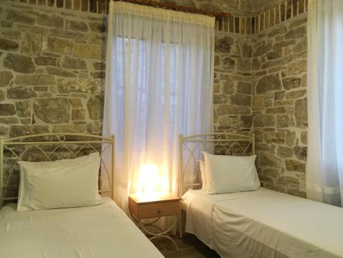 2 camas en una habitación con una pared de piedra en Villa Antonis, en Lákka