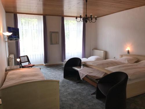 a bedroom with two beds and a table and windows at Rheinhotel Starkenburger Hof in Bingen am Rhein