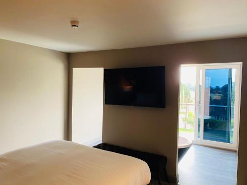 a bedroom with a bed and a television on the wall at Wildes Inns in Chesterfield
