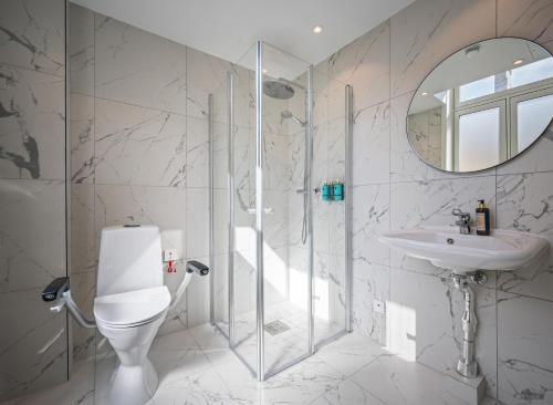 a bathroom with a toilet and a sink and a mirror at Karl Johan Hotel in Oslo