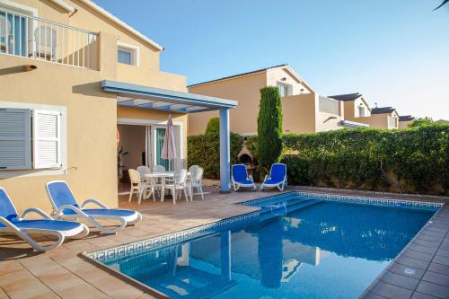 a villa with a swimming pool and chairs and a house at Sagitario Villas in Son Carrio
