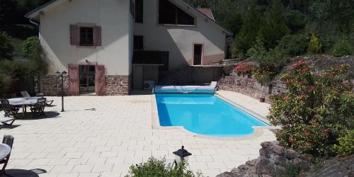 a swimming pool in front of a house at La Belle Charbonnière in La Grande Fosse
