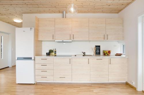 uma cozinha com armários de madeira e um frigorífico branco em House with fjord views Hommersåk ( stavanger, sandnes ) em Sandnes