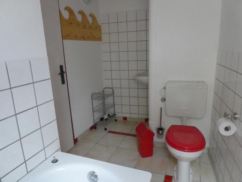 La salle de bains est pourvue de toilettes rouges et d'une baignoire. dans l'établissement Ferienwohnung Maidenhain, 