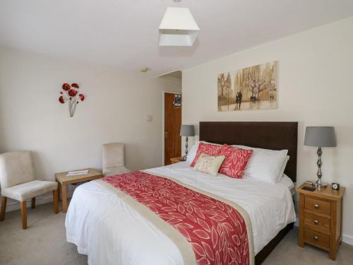 a bedroom with a large bed and a chair at The Malins in Moreton in Marsh