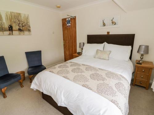 a bedroom with a large bed and two chairs at The Malins in Moreton in Marsh