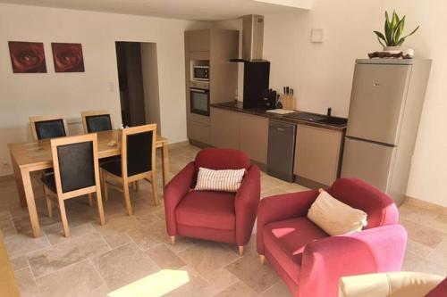 Il comprend un salon avec deux chaises et une table ainsi qu'une cuisine. dans l'établissement Ruby - Gîte 2 chambres dans vieux prieuré près de Carcassonne, à Sainte-Eulalie