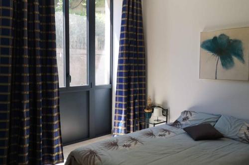 1 dormitorio con cama y ventana en Ruby - Gîte 2 chambres dans vieux prieuré près de Carcassonne en Sainte-Eulalie