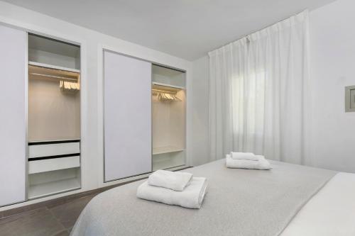 een witte slaapkamer met spiegels en een bed met handdoeken bij Luna Beach in Cabopino