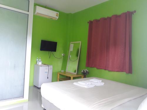 - une chambre verte avec un lit blanc et un miroir dans l'établissement ปอ อา ยอ รีสอร์ท, à Pai