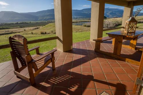 a wooden bench sitting on a porch with a table at Kwetu Guest Farm in Swellendam