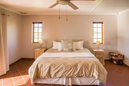 a bedroom with a bed with two night stands and two windows at Kwetu Guest Farm in Swellendam