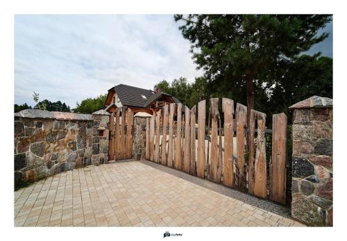 a wooden fence with a gate and a stone wall at BORYSÓWKA in Kopanica