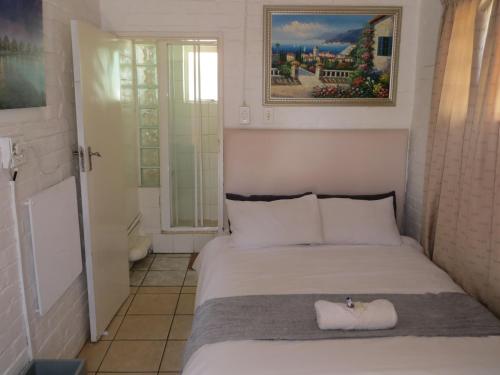 a small bedroom with a bed and a bathroom at The Swiss Guesthouse in Johannesburg
