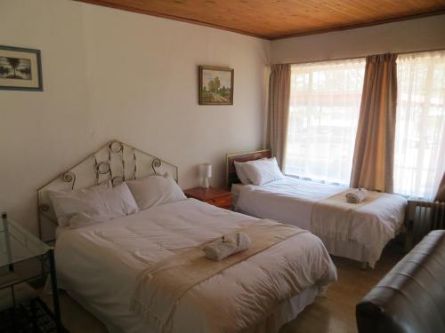 a bedroom with two beds and a couch and a window at The Swiss Guesthouse in Johannesburg