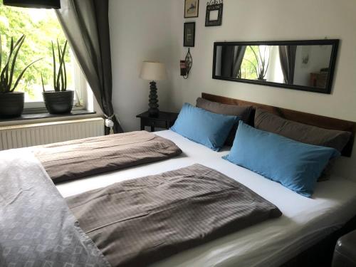 a bedroom with a bed with blue pillows and a mirror at Zweitheimat in Kalkar