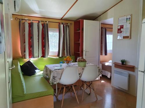 une salle à manger avec une table et un canapé vert dans l'établissement Monte da Caldeirinha, à Luz de Tavira