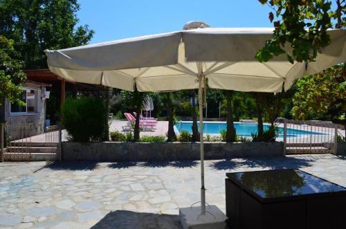 una sombrilla blanca grande frente a una piscina en Artemis Studios - Pool and garden, en Koskinou