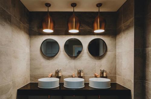 a bathroom with three sinks and three mirrors at Wildes Inns in Chesterfield