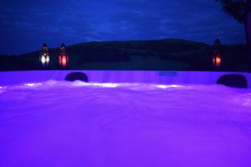 a pool with purple lighting in a backyard at night at Healing Pastures Farm in Llanbrynmair