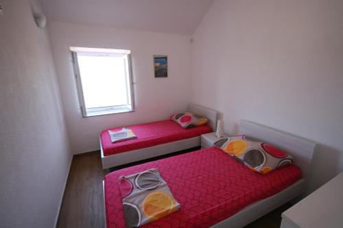 twee bedden in een kleine kamer met een raam bij House Sakarun with swimming pool in Veli Rat