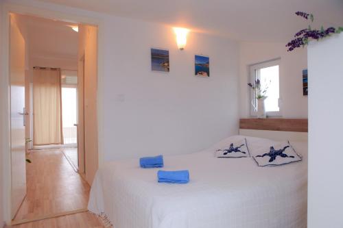 um quarto branco com uma cama com almofadas azuis em Apartments Villa Marija em Novigrad Dalmatia