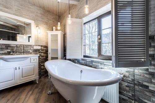 a bathroom with a white tub and a sink at Маєток "ZYMON & SKI" in Bukovel