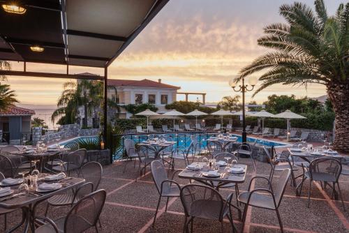 ein Restaurant mit Tischen und Stühlen und einem Pool in der Unterkunft Akti Taygetos - Conference Resort in Kalamata