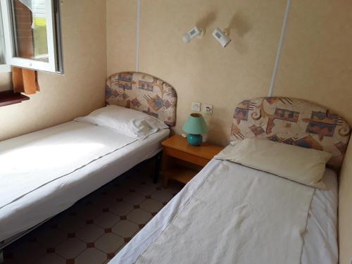 two beds in a small room with a night stand and a bedskirts at Mobil Home Fradin Parc de loisirs in Talmont