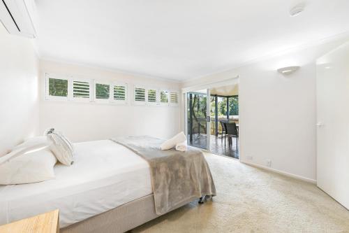 a white bedroom with a large bed and a balcony at Cabana @ Cupania in Mudjimba