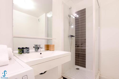 een witte badkamer met een wastafel en een douche bij Appart avec Parking Climatisation Loggia à la Cité du Vin in Bordeaux