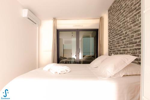 uma cama branca num quarto com uma parede de tijolos em Appart avec Parking Climatisation Loggia à la Cité du Vin em Bordeaux