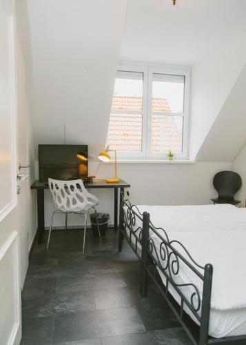 a bedroom with a bed and a desk and a chair at Gästehaus Vigliarolo gewerblich Jedes Zimmer eigenes Bad Gemeinschaftsküche in Elmshorn