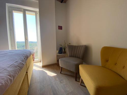 a bedroom with a bed and a chair and a window at Allegro Holiday in Nizza Monferrato