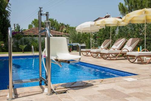 a pool with chairs and umbrellas next to a swimming pool at CRESCENT TWINS- BLUE VİLLA in Dalyan