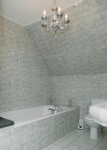 a bathroom with a tub and a toilet and a chandelier at Gästehaus Vigliarolo gewerblich Jedes Zimmer eigenes Bad Gemeinschaftsküche in Elmshorn
