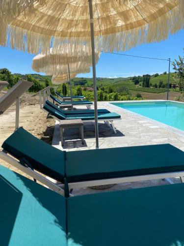 a group of lounge chairs under an umbrella next to a pool at Allegro Holiday in Nizza Monferrato