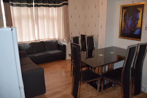 - une salle à manger avec une table, des chaises et un canapé dans l'établissement Three Bedroom Flat, Camborne Avenue W13, à Londres
